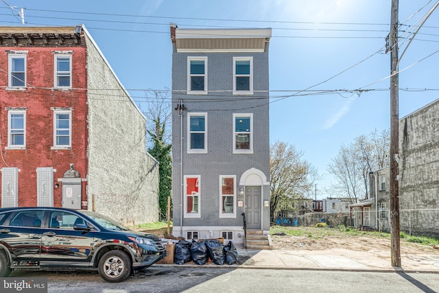 view of front of home featuring brick siding and fence