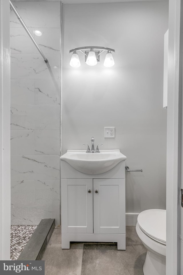 bathroom featuring vanity, tiled shower, and toilet