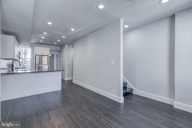 kitchen featuring dark wood-type flooring, stainless steel refrigerator, sink, and white cabinetry