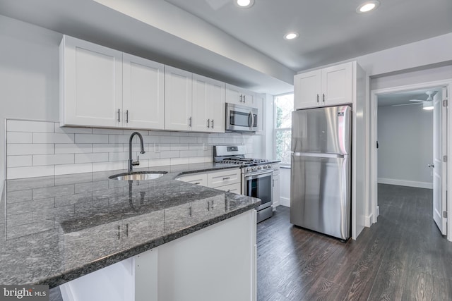 kitchen featuring dark wood-type flooring, sink, stainless steel appliances, kitchen peninsula, and white cabinetry