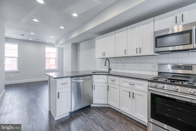 kitchen with stainless steel appliances, kitchen peninsula, dark hardwood / wood-style flooring, and white cabinetry