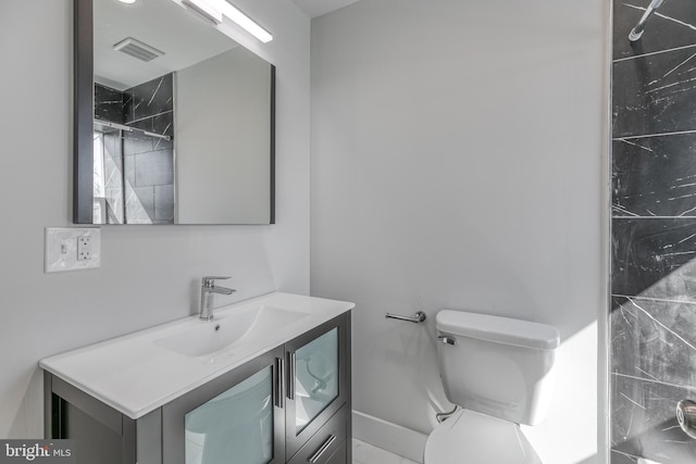 bathroom featuring a tile shower, vanity, and toilet