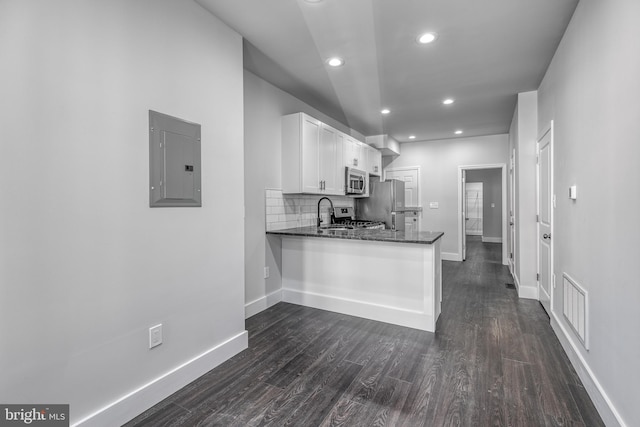 kitchen featuring electric panel, dark stone counters, stainless steel appliances, kitchen peninsula, and white cabinetry