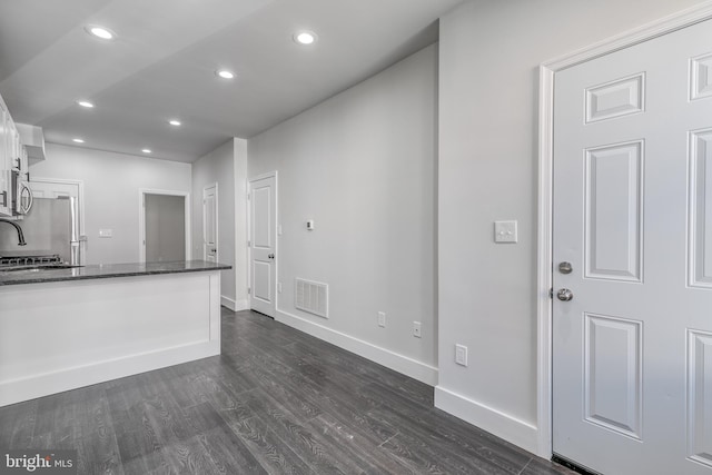 kitchen featuring dark wood-type flooring, stainless steel refrigerator, and white cabinets