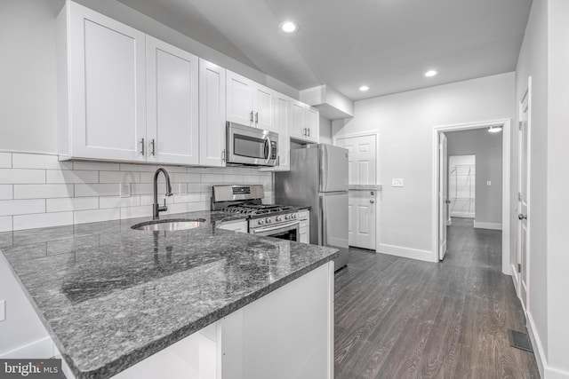 kitchen featuring white cabinets, sink, dark hardwood / wood-style flooring, kitchen peninsula, and appliances with stainless steel finishes