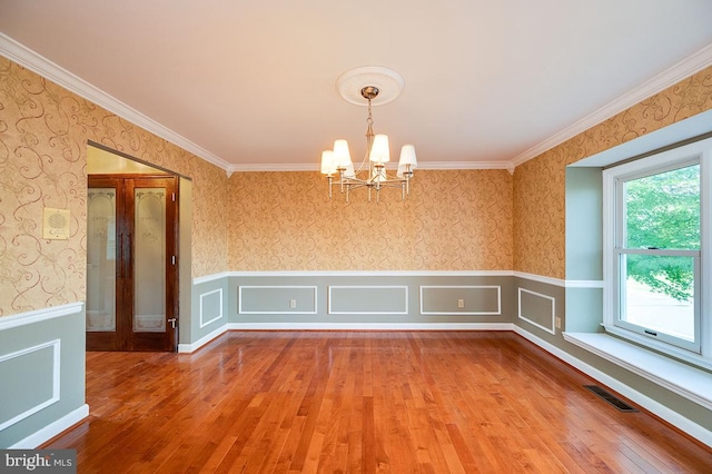 unfurnished room with ornamental molding, hardwood / wood-style flooring, and a notable chandelier