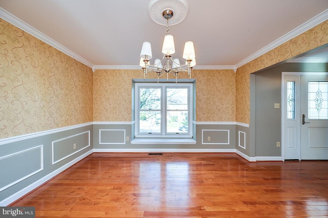 unfurnished dining area with wood-type flooring, ornamental molding, and a chandelier