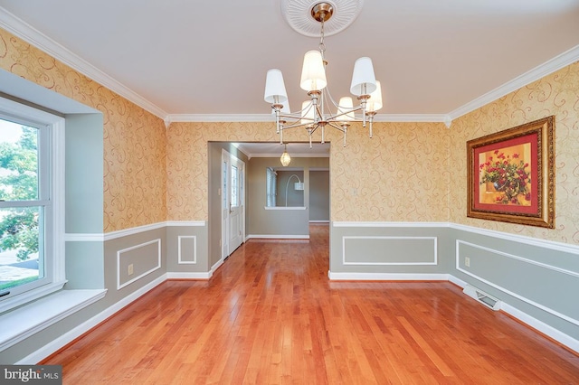 unfurnished dining area with a notable chandelier, hardwood / wood-style flooring, and crown molding