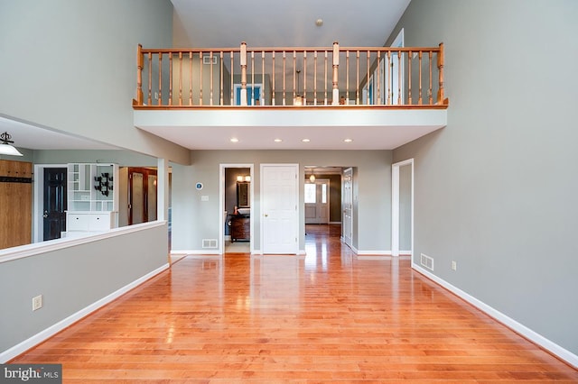 unfurnished living room featuring light hardwood / wood-style flooring and a high ceiling