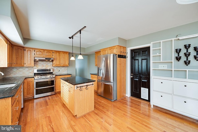 kitchen featuring sink, light hardwood / wood-style flooring, backsplash, stainless steel appliances, and a center island