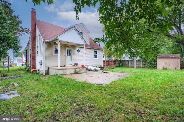 rear view of property with a lawn, a patio, and a storage unit