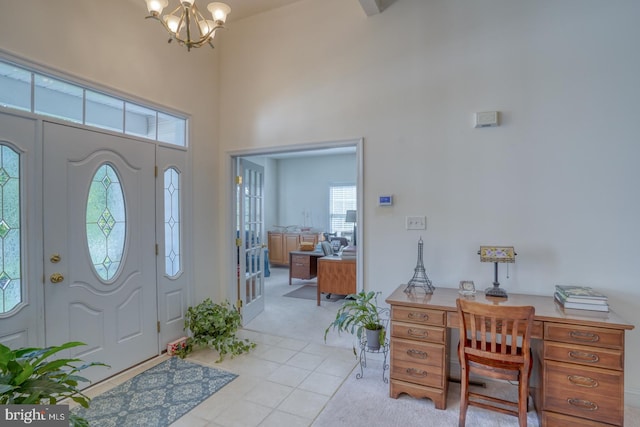 carpeted entryway featuring a wealth of natural light, a high ceiling, and a notable chandelier