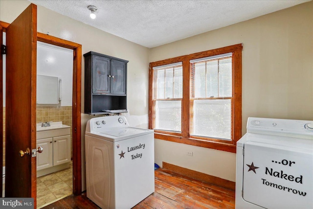 laundry area featuring cabinets, hardwood / wood-style floors, sink, washing machine and dryer, and a textured ceiling