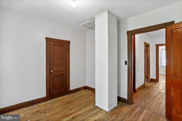 unfurnished room with light wood-type flooring and a textured ceiling