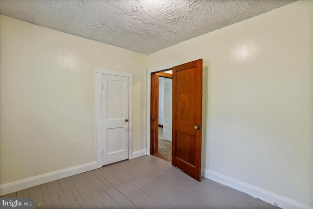 empty room with a textured ceiling and light wood-type flooring