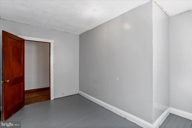 unfurnished room with a textured ceiling and dark hardwood / wood-style flooring