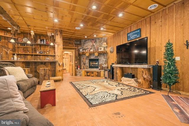 living room featuring wooden walls, a stone fireplace, and hardwood / wood-style flooring