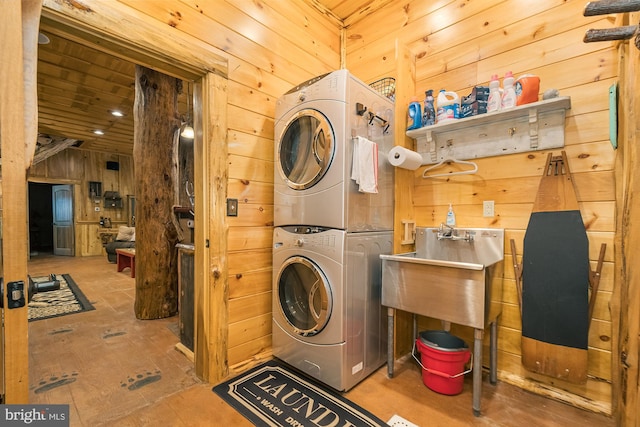 laundry area featuring stacked washing maching and dryer and wooden walls