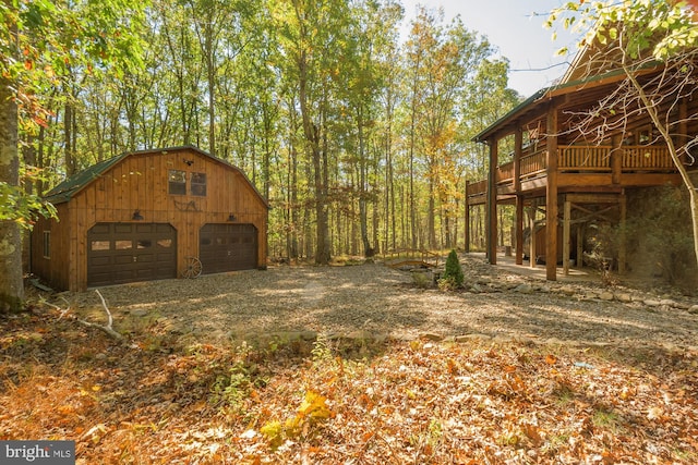 view of yard with a garage, a deck, and an outbuilding