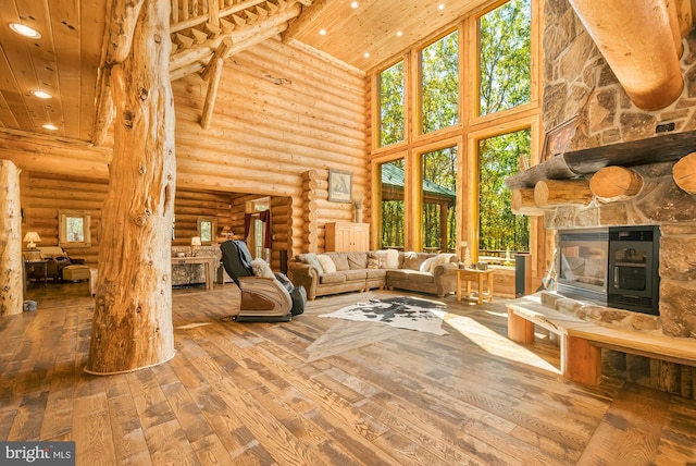 unfurnished living room with wood-type flooring, a fireplace, wood ceiling, high vaulted ceiling, and rustic walls