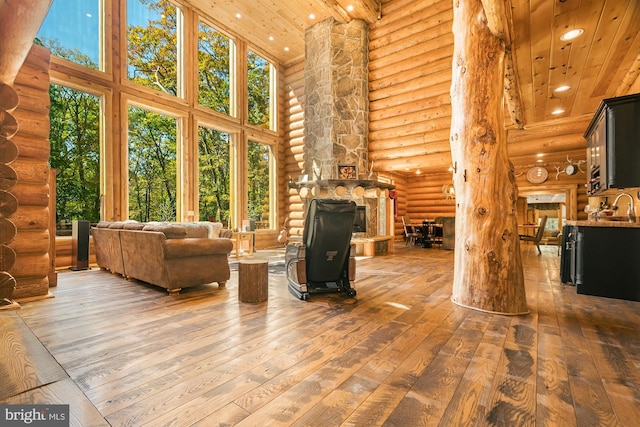 living room featuring a towering ceiling, a fireplace, wood ceiling, hardwood / wood-style flooring, and rustic walls