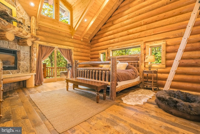 bedroom featuring a stone fireplace, light hardwood / wood-style floors, wooden ceiling, high vaulted ceiling, and rustic walls