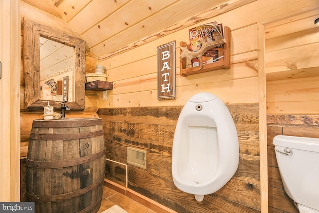 bathroom featuring toilet, lofted ceiling, and wooden walls