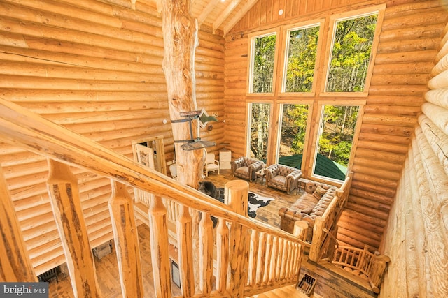 staircase featuring log walls, wood-type flooring, and vaulted ceiling