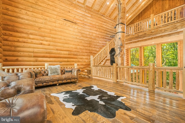 unfurnished living room featuring hardwood / wood-style floors, beamed ceiling, wooden ceiling, log walls, and high vaulted ceiling