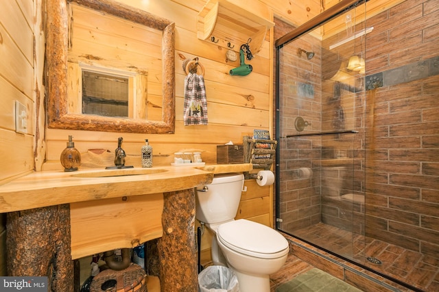 bathroom with a shower with door, sink, wooden walls, and toilet