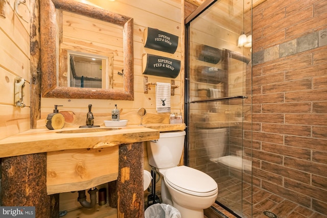 bathroom with vanity, toilet, a shower with shower door, and wooden walls