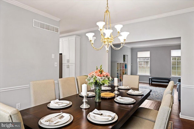 dining area featuring ornamental molding, a chandelier, and dark hardwood / wood-style flooring