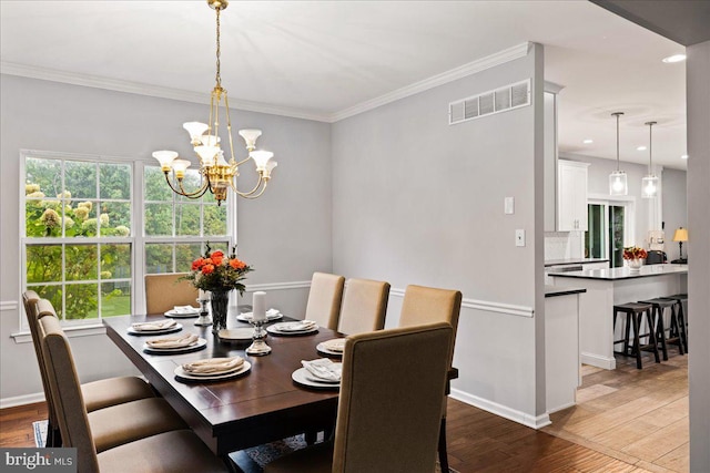 dining area with crown molding, a notable chandelier, and dark wood-type flooring