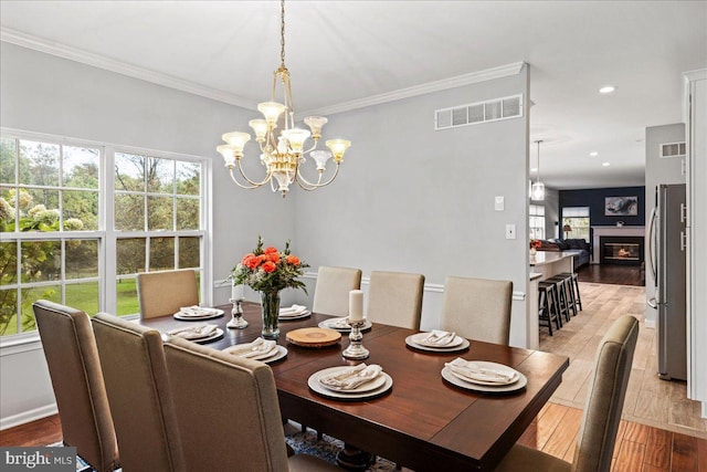 dining area featuring ornamental molding, light hardwood / wood-style flooring, and a notable chandelier