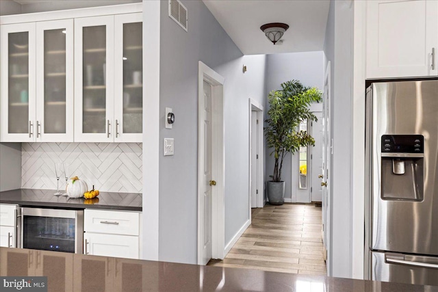 kitchen with white cabinets, beverage cooler, light hardwood / wood-style flooring, and stainless steel refrigerator with ice dispenser