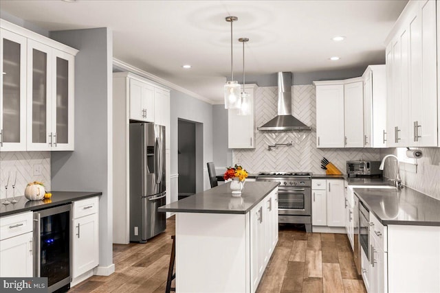 kitchen featuring a kitchen island, stainless steel appliances, wall chimney exhaust hood, decorative light fixtures, and wine cooler