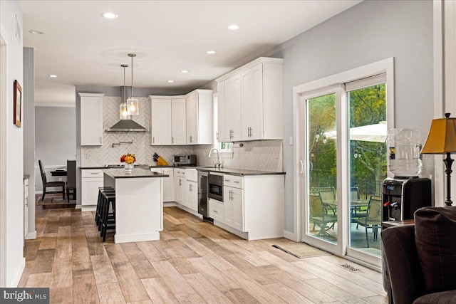 kitchen featuring white cabinets, hanging light fixtures, and light hardwood / wood-style flooring