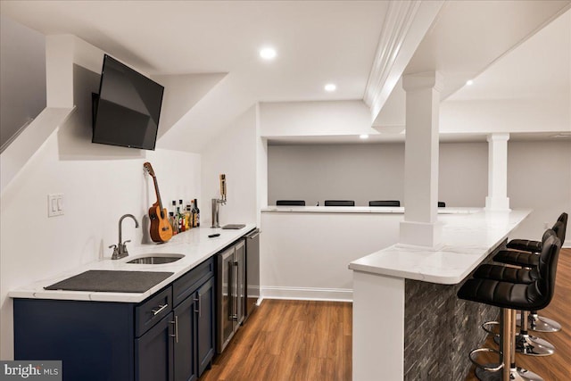 bar with wine cooler, hardwood / wood-style flooring, light stone countertops, and sink