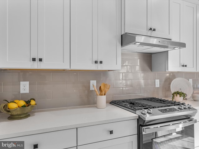 kitchen with tasteful backsplash, gas stove, and white cabinetry