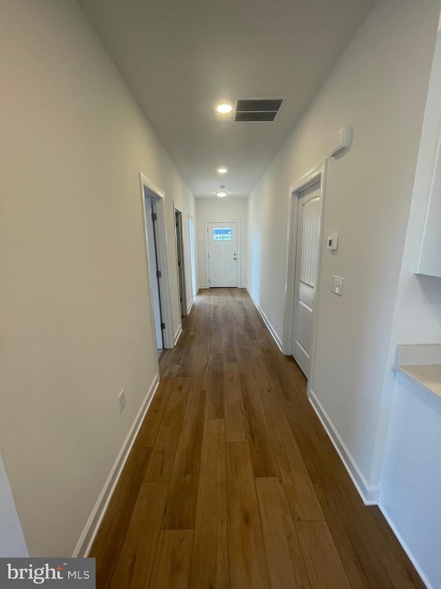 corridor featuring baseboards, visible vents, and dark wood-style flooring