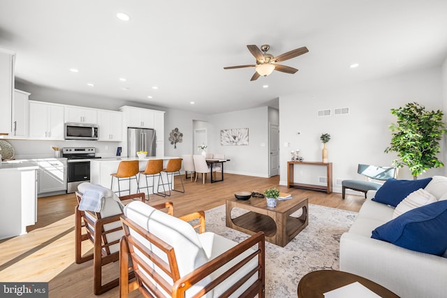 living room featuring ceiling fan and light hardwood / wood-style flooring