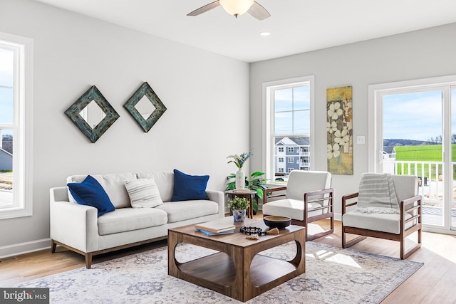 living area with light wood-style floors, ceiling fan, visible vents, and baseboards