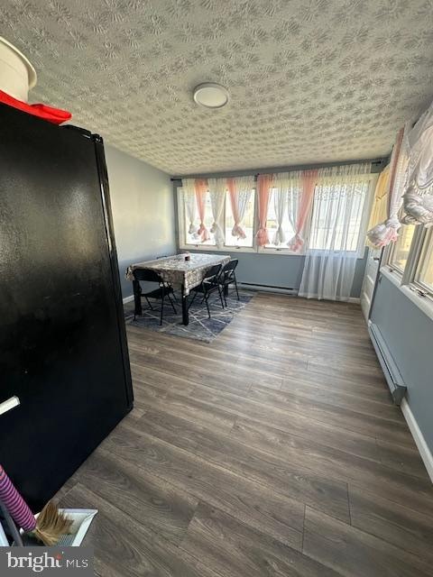 dining space featuring a textured ceiling, dark hardwood / wood-style flooring, and a baseboard heating unit