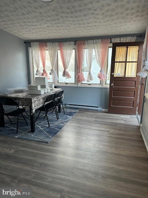 dining room with a textured ceiling, dark wood-type flooring, and baseboard heating