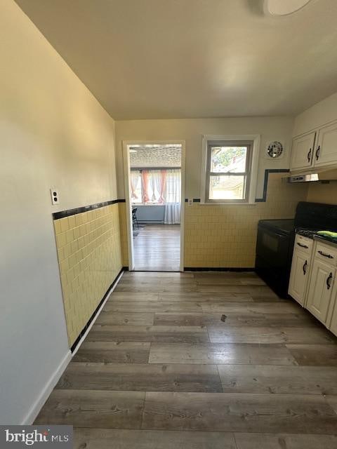 kitchen with black range with electric cooktop, dark wood-type flooring, white cabinetry, and tile walls