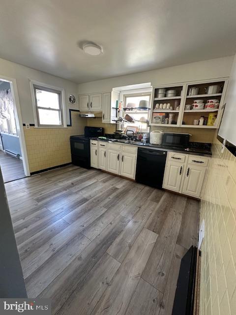 kitchen with white cabinets, light wood-type flooring, and black appliances