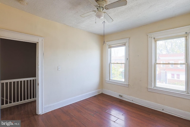 spare room featuring ceiling fan, a healthy amount of sunlight, a textured ceiling, and dark hardwood / wood-style floors