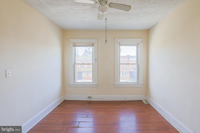 unfurnished room with a textured ceiling, a wealth of natural light, and dark hardwood / wood-style flooring