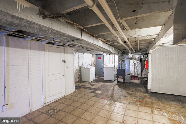 basement with water heater, washing machine and clothes dryer, and heating unit