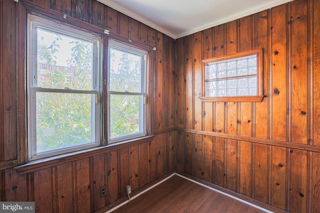 unfurnished room with ornamental molding, wooden walls, and dark wood-type flooring